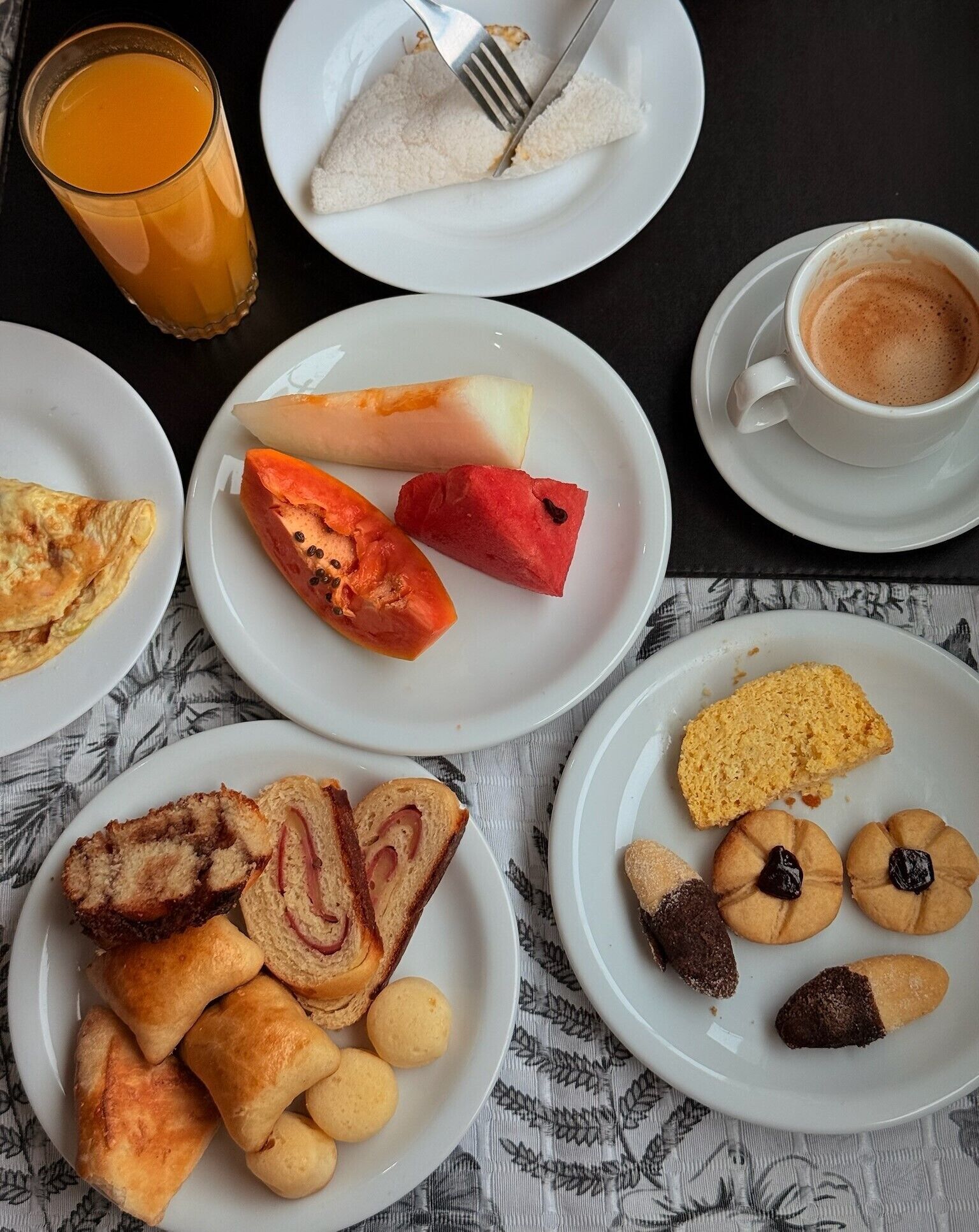 Ein gedeckter Frühstückstisch mit Speisen, einem Glas Orangensaft und einer Tasse Kaffee.
