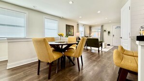 A dining area with a round table and four chairs, a kitchen area with a counter and cabinets, and a door leading to another room. - Cute & Cozy House in Quiet Blue Ash Neighborhood (Blue Ash)