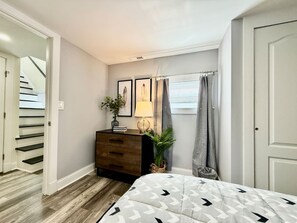 A bedroom with a bed, a dresser, a lamp, and a plant. - Cute & Cozy House in Quiet Blue Ash Neighborhood (Blue Ash)