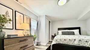 A modern bedroom with a large bed, a dresser, and framed artwork on the wall. - Cute & Cozy House in Quiet Blue Ash Neighborhood (Blue Ash)