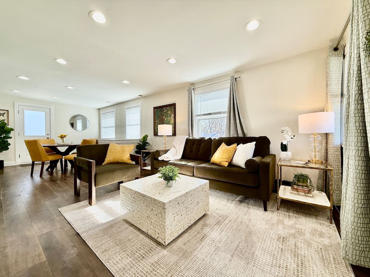 A spacious living room with a sofa, coffee table, and a dining area with chairs and a table.
