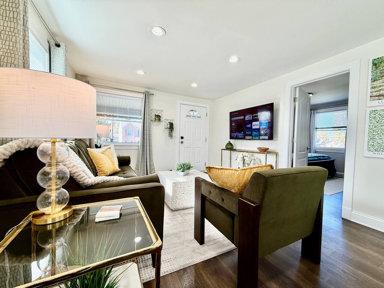 Un salon moderne avec un canapé, un fauteuil, une table basse et un téléviseur fixé au mur.