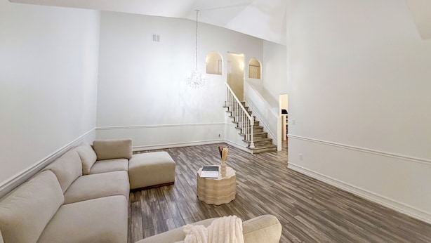 A spacious living room with a large L-shaped sectional sofa, a round coffee table, and a staircase leading to an upper floor. - Snowbird & Alta Ski Retreat + Walk to Ski Bus + High Ceilings + Newly Remodeled (Sandy)
