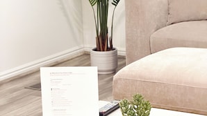 A living room with a beige sofa, a potted fern, a small succulent plant, and a welcome sign on a table. - Snowbird & Alta Ski Retreat + Walk to Ski Bus + High Ceilings + Newly Remodeled (Sandy)