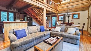 Ein geräumiges Wohnzimmer mit einer großen Eckcouch, einem Holztisch und einer Treppe, die in ein Obergeschoss führt.