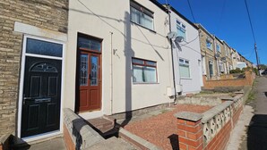A row of terraced houses with a brick front, a white door, and a small front garden. - Ushaw Hilltop View- Comfortable 2-Bed Home Near Durham University & City (Ushaw Moor)