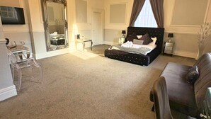 Ein geräumiges Schlafzimmer mit einem großen Bett, einer Kandelaber, einem Spiegel und einem Fernseher.