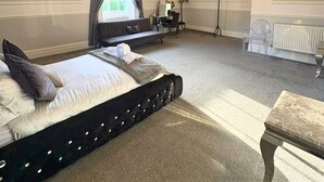 Ein geräumiges Schlafzimmer mit einem großen Bett, einer Kristallleuchter, einem Schreibtisch und einer Heizung.