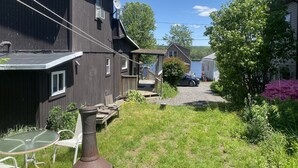 A residential area with a large dark wooden house, a smaller house, and a car parked in the driveway. There is a garden with various plants and a table with chairs. - Newton Lake (Carbondale)