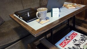 A cozy room with a wooden wall, a couch, a coffee table with a laptop, a mug, a book, and a Monopoly board game. - Newton Lake (Carbondale)