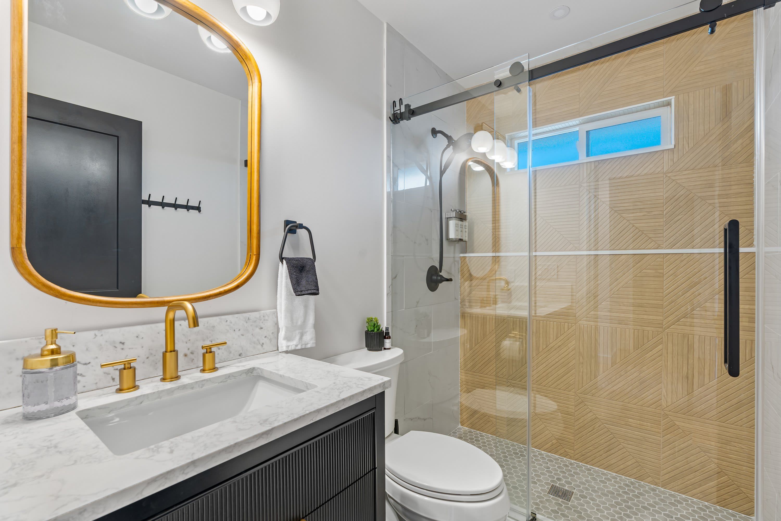 A modern bathroom with a large mirror, a shower, and a toilet.