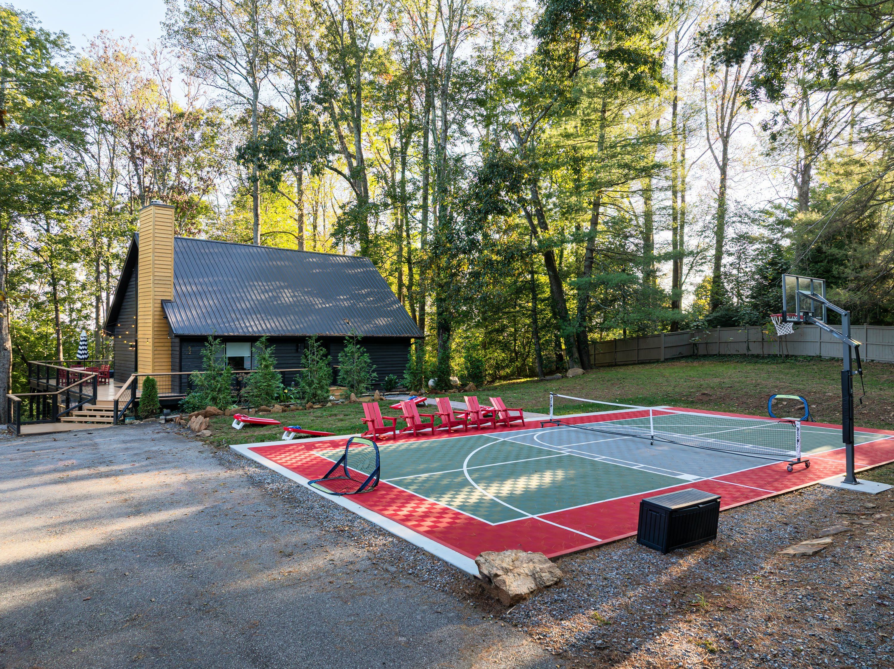 Un terrain de basket avec des chaises rouges et un petit bâtiment situé dans une zone boisée.