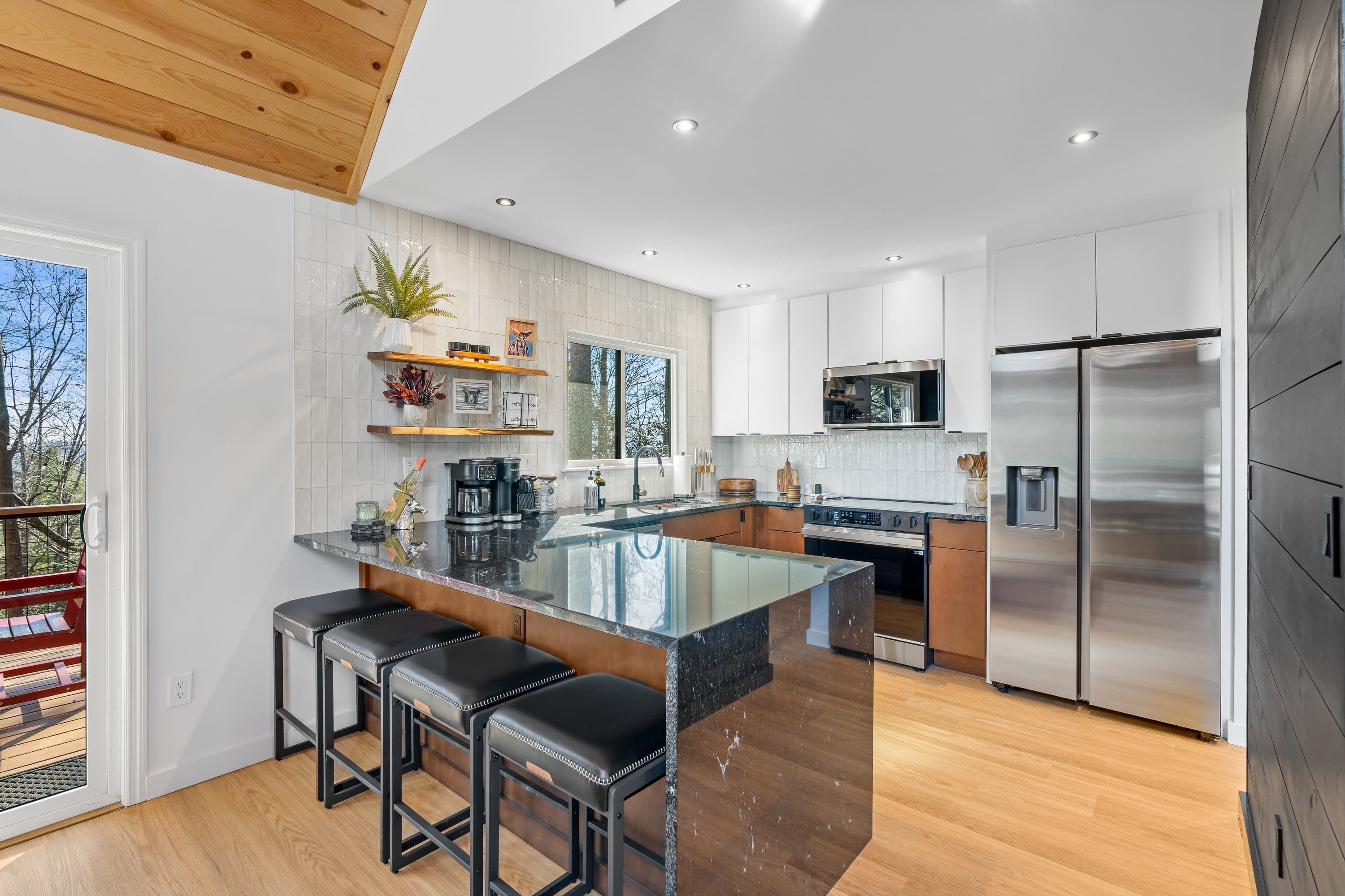 A modern kitchen with a central island, stainless steel appliances, and wooden flooring.