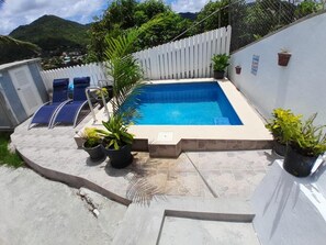 A swimming pool with lounge chairs, potted plants, and a white fence. - Cozy 1-bedroom apartment in fantastic Castries with AC (Monchy)