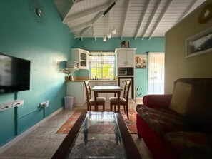 A living room with a TV, a dining table, and a red sofa. - Cozy 1-bedroom apartment in fantastic Castries with AC (Monchy)