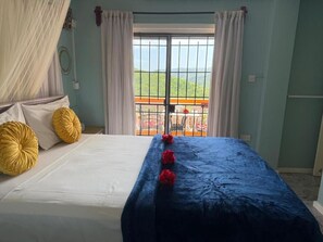 A bed with white and yellow pillows, a blue bedspread, and red flowers. - Cozy 1-bedroom apartment in fantastic Castries with AC (Monchy)