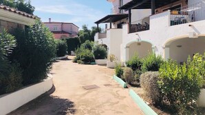 Una calle residencial con un sendero estrecho, bordeada de vegetación y edificios con balcones.