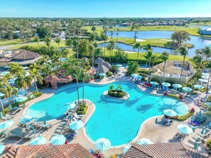 A resort with a large central pool, multiple smaller pools, and a golf course in the background. -  resort-style living in this beautiful two-bedroom condo in Lely resort (Naples)