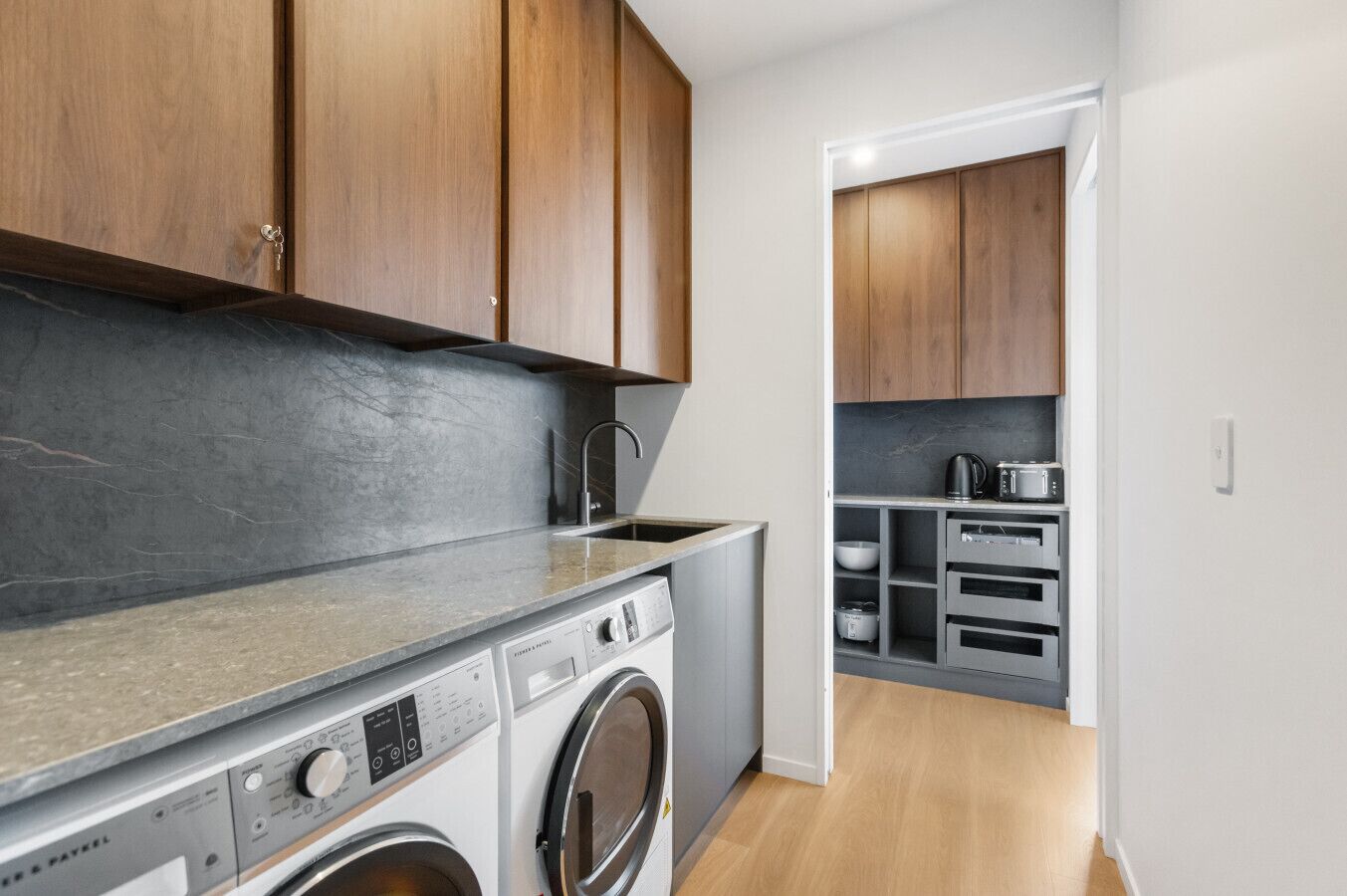 Una cocina moderna con armarios de madera, lavadora integrada y encimera con lavamanos.