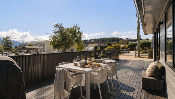 A wooden deck with a table set for dining, outdoor seating, and a view of the surrounding area. - Central Wanaka Escape | Lake Views | Walk to Town | Deck & BBQ (Wānaka)