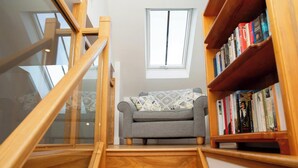 Eine Treppe führt zu einer kleinen Sitzecke mit einem Sofa und einem Bücherregal voller Bücher.