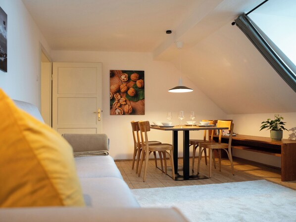 A cozy loft apartment with a dining area, a sofa, and a large window. - Idyllic apartment on the Ritten - peace, nature & views of the Dolomites. Mobilcard incl. (Trentino-Alto Adige)