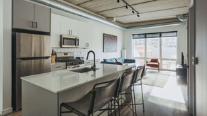 A modern kitchen with a central island, stainless steel appliances, and a large window providing natural light. - Luxury Penthouse Loft w/Terrace  507 | River North (Chicago)