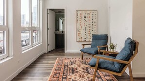 A spacious room with large windows, a wooden floor, and a blue chair. - Luxury Penthouse Loft w/Terrace  507 | River North (Chicago)