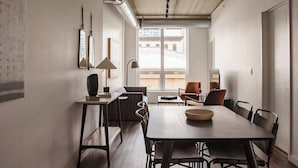 A modern dining area with a large table, chairs, and a view of the city through a large window. - Luxury Designer Loft 302 | River North (Chicago)
