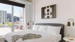 Et moderne hotelværelse med en stor seng, udsigt over byen og minimalistisk indretning.