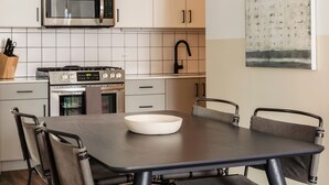 Eine moderne Küche mit Edelstahlgeräten, weißen Schränken und einem Esstisch mit Stühlen.