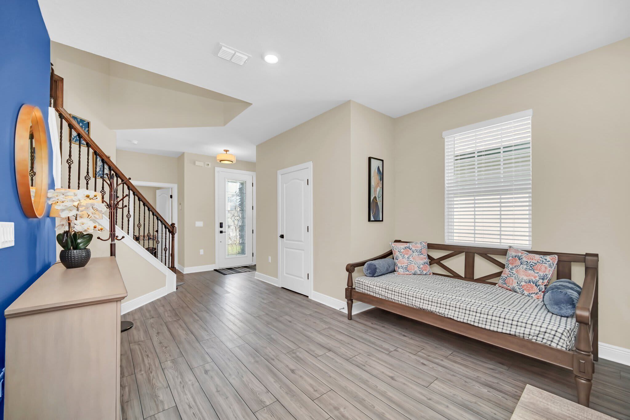 A spacious living area with a wooden bench, a staircase, and a door leading to another room.