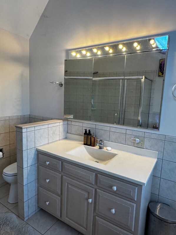 A bathroom with a vanity, mirror, and a toilet.