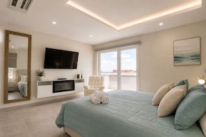 Quarto com cama, televisão, janela ampla e varanda.