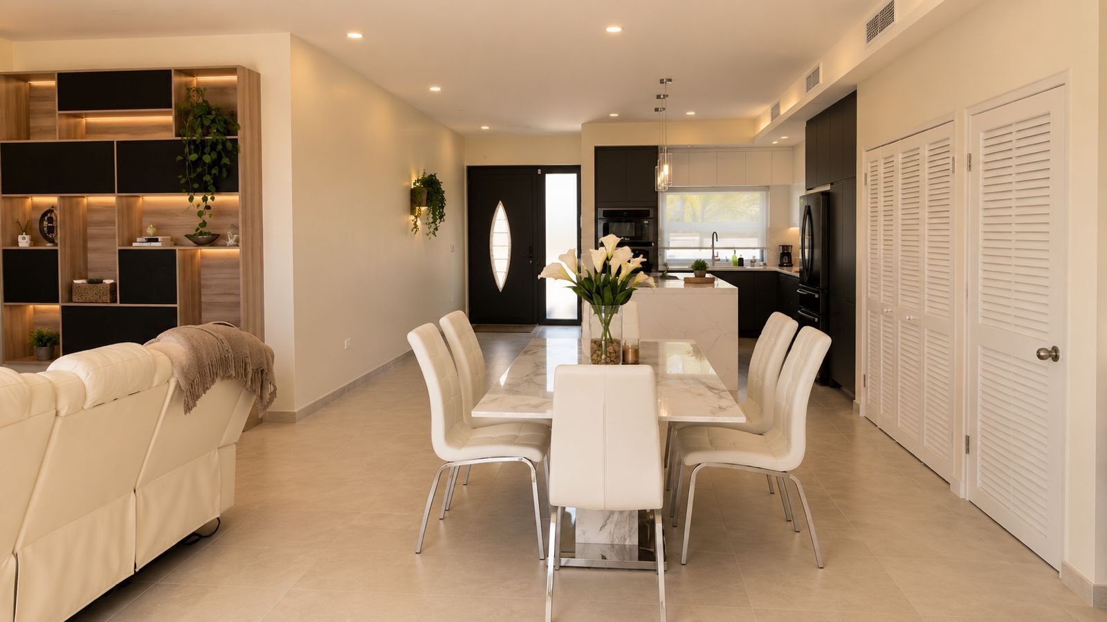 Un interior moderno con comedor, cocina y sala de estar con sofá y estanterías.