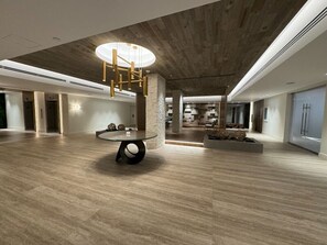 Eine großzügige Lobby mit einem modernen Kronleuchter, einem runden Tisch und einer Wand mit Steinakzenten.