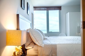 Ein Schlafzimmer mit Bett, Nachttisch, Lampe, Fenster mit Jalousien und Kleiderschrank.