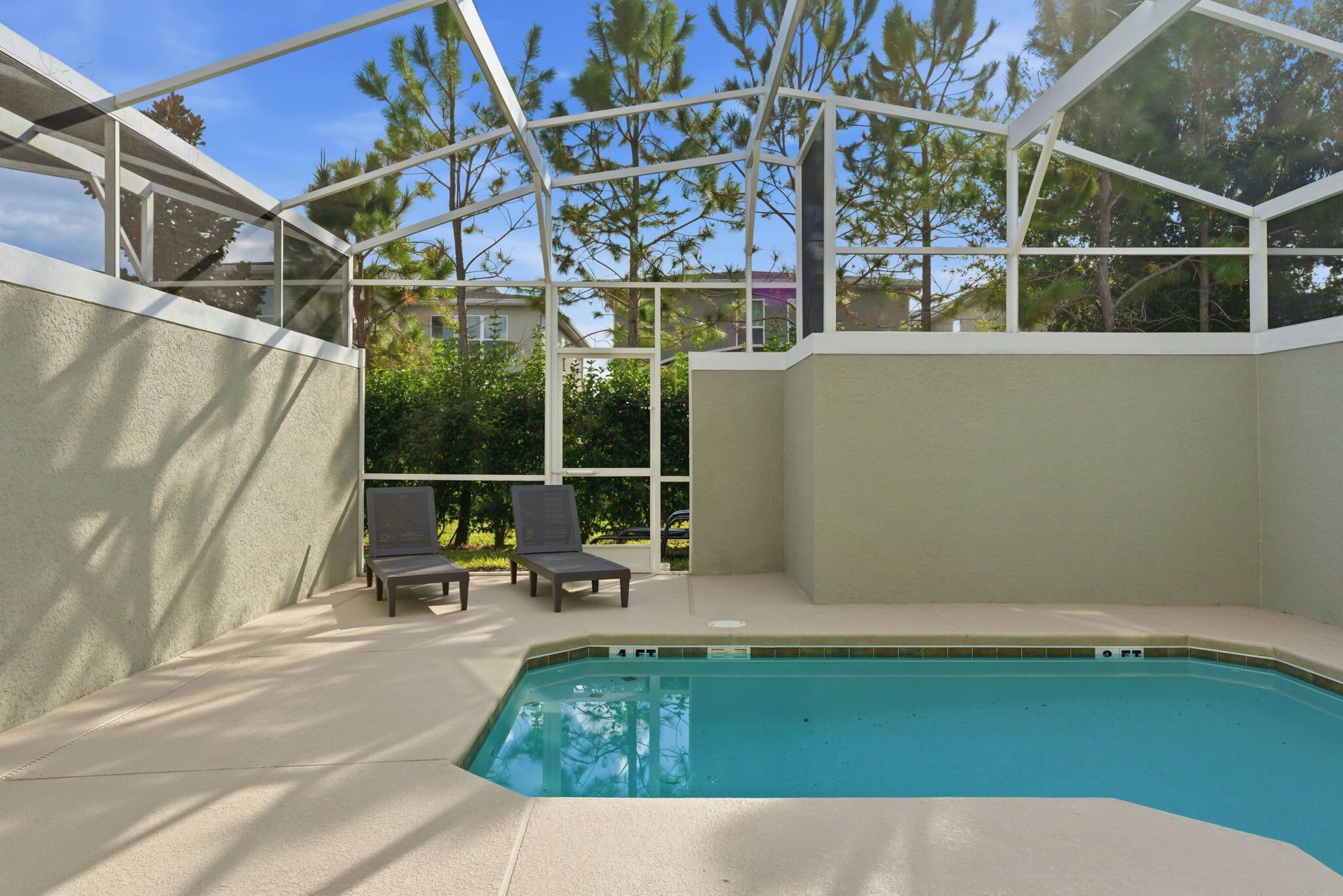 Una piscina interna con copertura in vetro, due lettini e vista su alberi e edifici.