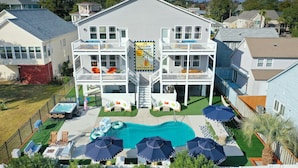A two-story house with a pool, outdoor seating, and a sign advertising Myrtle Beach, SC. - Golf Sim, Theater, Games, Walk to Beach, Sleeps 28 (North Myrtle Beach)