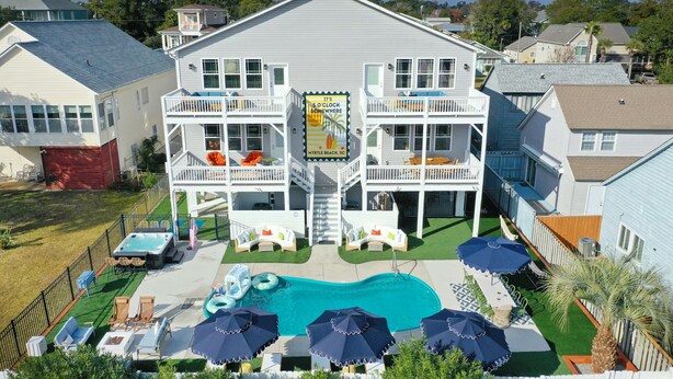 A two-story house with a pool, outdoor seating, and a sign advertising Myrtle Beach, SC. - Golf Sim, Theater, Games, Walk to Beach, Sleeps 28 (North Myrtle Beach)