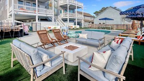 A poolside area with outdoor seating, a fire pit, and a two-story building with balconies. - Golf Sim, Theater, Games, Walk to Beach, Sleeps 28 (North Myrtle Beach)