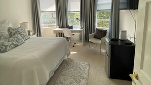 Et hotelværelse med en stor seng, et skrivebord, en stol, et fjernsyn og udsigt til grøn natur.
