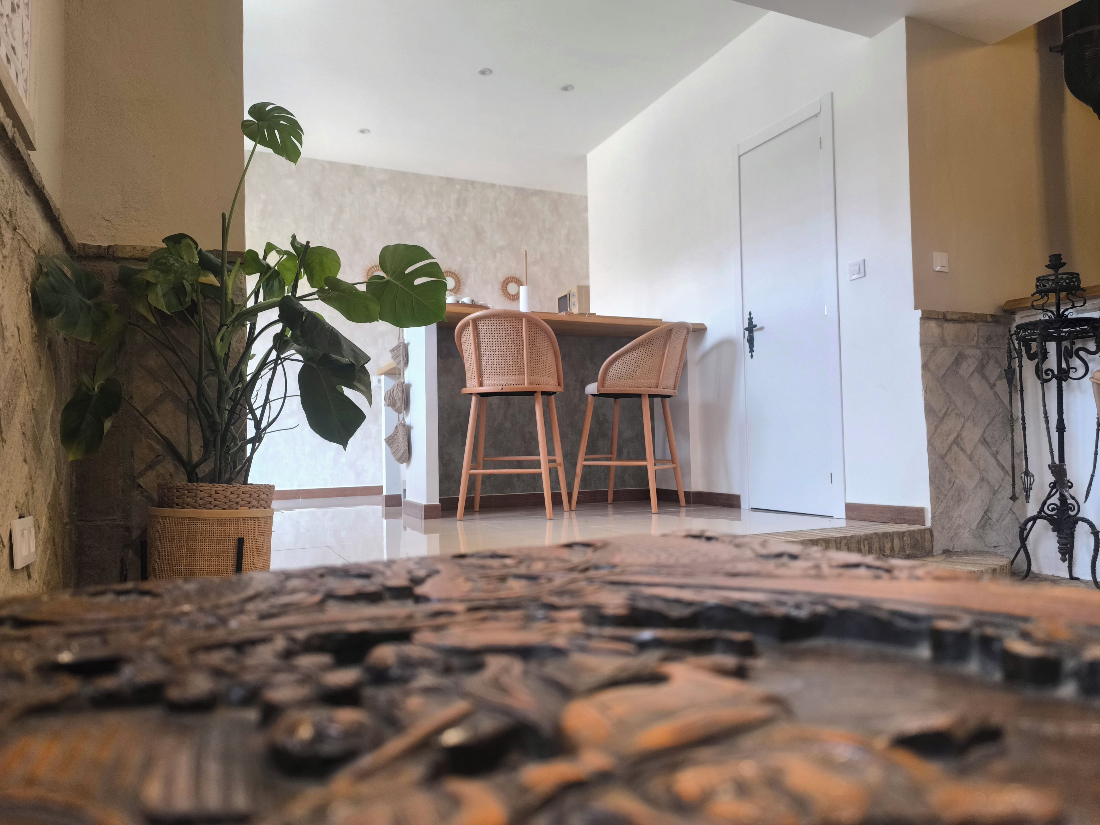 Quarto com área de jantar com duas cadeiras de vime, um vaso de planta e uma porta branca.