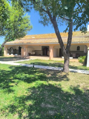 Un edifici amb teulada a falça, terrassa coberta i jardí.