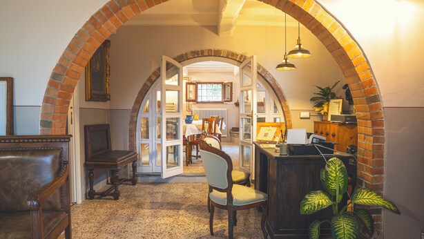 Un intérieur avec une arche en briques menant à un coin repas, un bureau en bois et une chaise.
