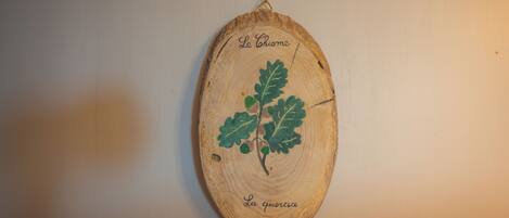 Eine Holzscheibe mit Blatt und Schriftzug, die an einer Wand angebracht ist.
