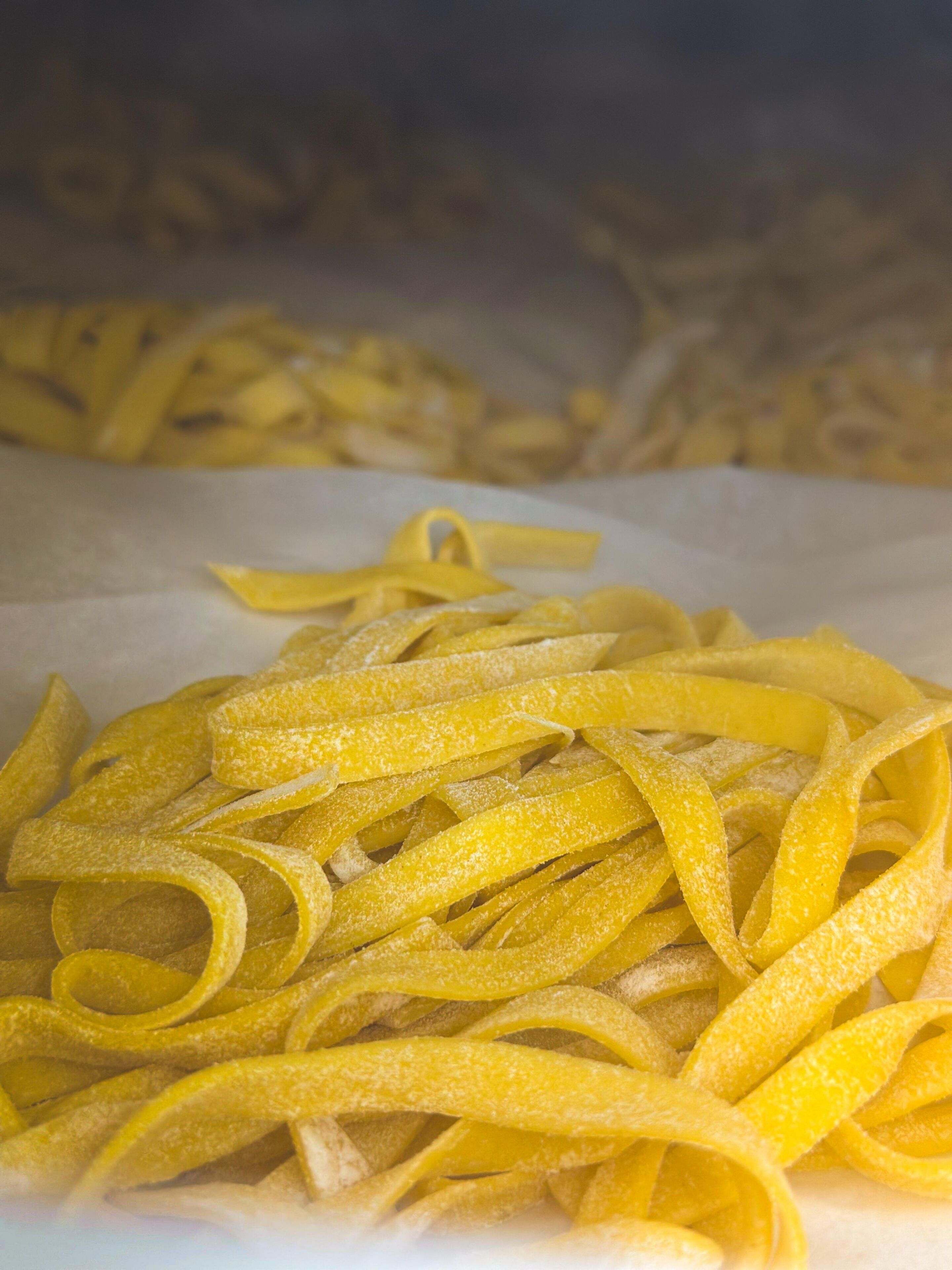 Een hoop gele pasta op een witte ondergrond.