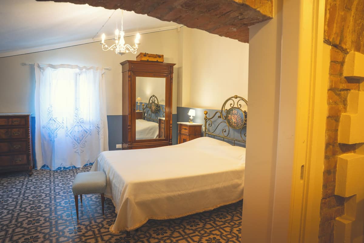 Un dormitorio con una cama, un aparador de madera, un espejo y un suelo estampado.