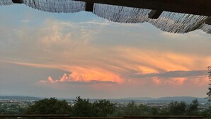 Un espace de restauration en plein air avec une table dressée pour deux personnes, entourée de chaises, de bottes de foin et offrant une vue pittoresque sur la campagne.