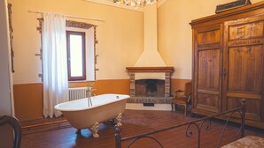 Une pièce avec une baignoire sur pieds, une cheminée et un meuble en bois.